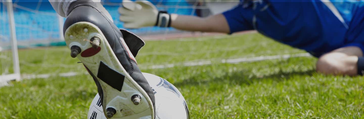 Close-up of foot kicking soccer ball.