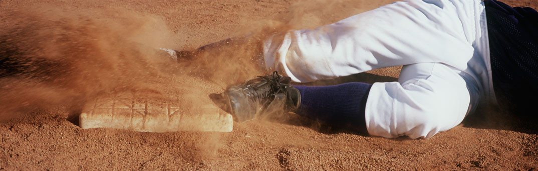 Close up of baseball player sliding into a base.